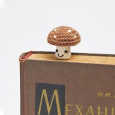 a small crocheted mushroom sitting on top of a book with the word mexihi written below it