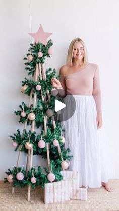 a woman standing next to a christmas tree