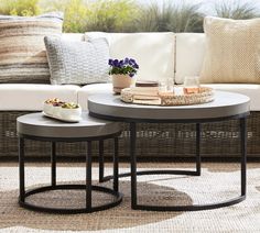 two round tables sitting on top of a rug next to a couch and table with flowers