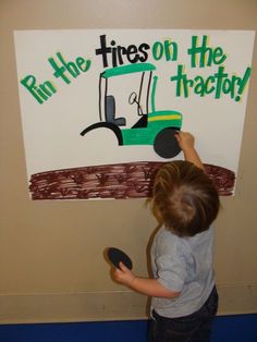 a young boy is painting a sign on the wall that says run the tires on the tractor