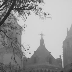 an old church with steeples and a cross on it's roof in the fog