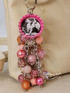 a pink and orange beaded keychain hanging from a beige bag with a picture on it