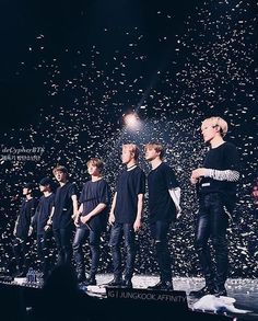 a group of men standing on top of a stage with confetti in the air