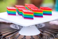 rainbow desserts are arranged on a white cake plate