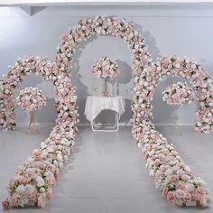 a white table topped with lots of flowers next to a floral arch covered in pink and white flowers