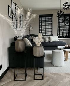 a living room with black couches and white rugs on the wooden flooring