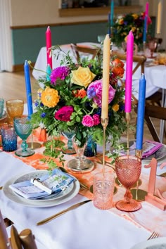 the table is set with colorful flowers and candles