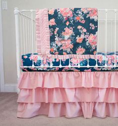 a baby crib with pink and blue bedding on it's bottom tier