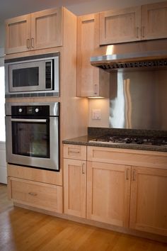 a kitchen with wooden cabinets and stainless steel oven, microwave and stove hood in it