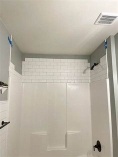 an empty bathroom with white tile walls and flooring, including a walk in shower