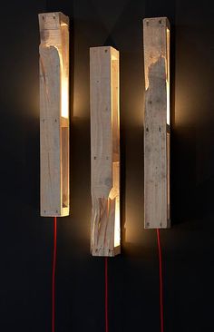 three wooden pieces with lights on them hanging from the wall next to each other in front of a black background