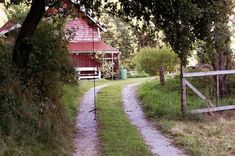 a red barn sitting on the side of a road next to a lush green field