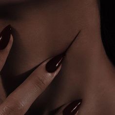 a woman's hand with long nails and dark brown nail polish on her body