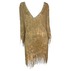 Presenting a stunning beaded gold fringe Roberto Cavalli mini dress. From the Fall/Winter 2002 collection, this 70s-inspired cropped-sleeve mini dress debuted on Alec Week and is covered in strands of tiny gold-tone beads that playfully sway with every movement. The dress is made complete with rhinestone details around the deep v-neckline, at the cuffs, and below the hips. Beyonce wore an identical dress to the 2002 Los Angeles premiere of 'Austin Powers in Goldmember'. This truly spectacular sparkly hand-beaded Roberto Cavalli dress is a must-have stand-out piece. Approximate measurements: Size - M Bust: 32 - 34" Waist: 30 -34" Hips: 40 - 42" Shoulder to hem: 31" (not including fringe off hem) Shoulder to cuff: 19" Underarm to cuff: 16" 100% silk Beyonce Gold Dress, Roberto Cavalli Runway, Roberto Cavalli Dress, Cavalli Dress, Austin Powers, Gold Fringe, Cute Dress Outfits, New Years Dress, 70s Inspired