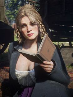 a woman holding an open book in her right hand and looking at the camera while sitting down