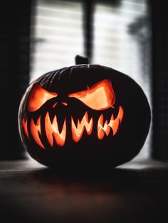 a carved jack o lantern sitting on top of a wooden table next to a window