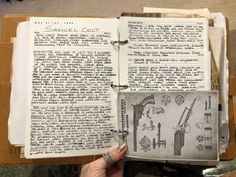 an open book with drawings on it and writing in the pages is being held by a woman's hand