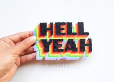 a hand is holding a piece of bead art that says hell yeah on it