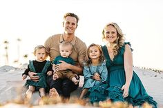 a man and two women are sitting on the sand with their children