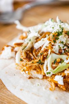 a tortilla topped with shredded cheese and other toppings on a wooden table