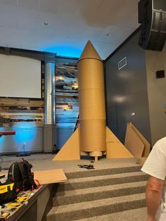 a man is standing in front of a projector screen with a rocket on it