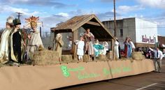 people are standing on top of hay bales in front of a small building with a nativity scene