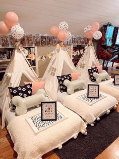 a room filled with lots of white furniture covered in pink and black pillows next to balloons