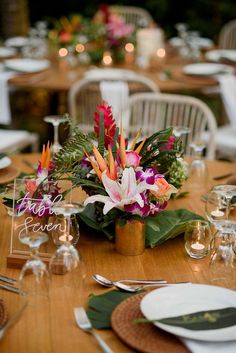 a wooden table topped with lots of white and pink flowers on top of it's centerpiece