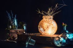 a person lighting a sparkler in a jar on top of a wooden table next to other items