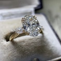 an oval diamond ring sits in a box