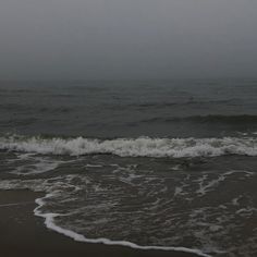 the waves are coming in to shore on an overcast, gloomy day at the beach