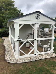 a white chicken coop sitting on top of a grass covered field