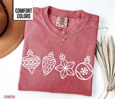 You will love this Comfort Colors Christmas ornament shirt. It has an adorable Christmas ornament design on the front.  This would be perfect for any woman to wear anywhere this holiday season. It comes in the popular colors espresso, berry, crimson, moss and light green for a festive Christmas look. Comfort Colors T shirt Details: 100% ring-spun cotton Medium fabric (6.1 oz/yd² (206.8 g/m Relaxed fit Sewn-in twill label T shirt Care instructions: Machine wash: cold (max 30C or 90F); Do not blea Ornament Shirt, Ornament Design, Women Christmas, Popular Colors, Ornaments Design, Christmas Tees, Shirt For Women, Merry Xmas, Cute Christmas