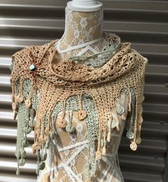 a mannequin wearing a crocheted shawl with buttons and chains on it