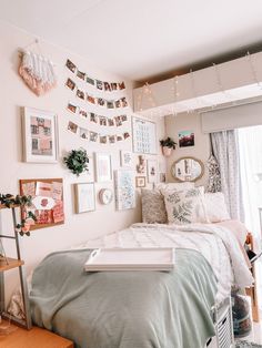 a bed room with a neatly made bed and lots of pictures on the wall above it