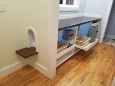 a cat house built into the side of a wall in a room with hardwood floors