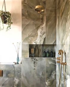 a bathroom with marble tiles on the walls and floor, including a shower head in the corner