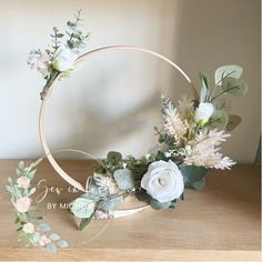 a wooden hoop with flowers and greenery on it sitting on top of a table