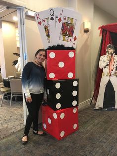 a woman standing next to a tower made out of dices and playing card suits