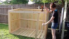 a woman is working on a wooden storage box in the yard with tools and hammers