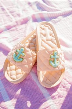 a pair of slippers sitting on top of a pink blanket