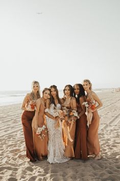 a group of women standing next to each other on top of a sand covered beach