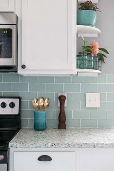 a kitchen with white cabinets and green tile backsplash