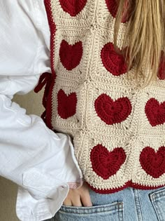 the back of a woman's sweater with crocheted hearts in red and white