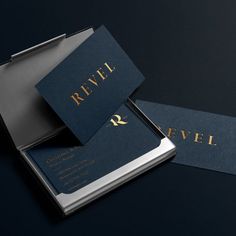 two black and gold business cards with the word revel written on them, sitting next to each other