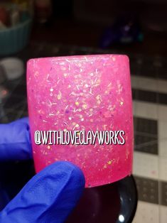 a person in blue gloves holds up a pink mug with glitter on it and the words wthlove clay works