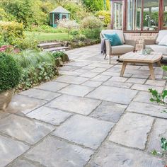 an outdoor patio with stone pavers and potted plants on the side, surrounded by greenery