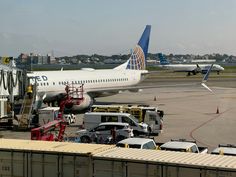 an airplane parked on the tarmac with other vehicles around it and trucks surrounding it