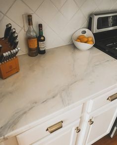 a kitchen counter with white marble top and gold pulls on the drawer knobs next to it