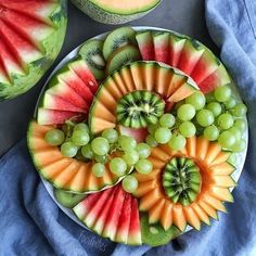 watermelon, grapes, and melon slices arranged on a plate with blue napkins